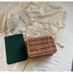 Close-up of retro woven straw handbag featuring elegant pearl handle and drawstring pouch