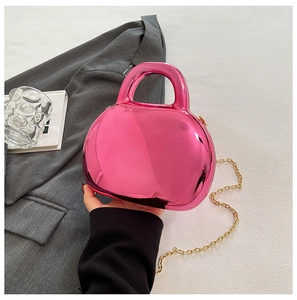 Detail of glossy metallic magenta shell bag with golden chain and sleek top handle