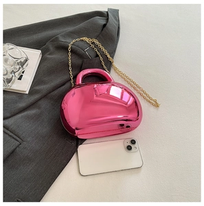 Macro detail of glossy pink acrylic shell bag with golden metal chain on a grey blazer