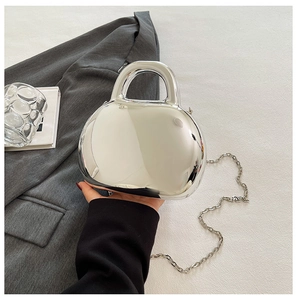 Detail of silver mirror acrylic shell bag with a detachable fine chain strap and top handle