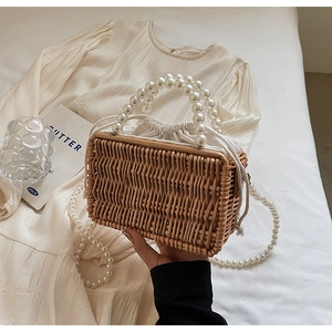 Close-up of woven straw handbag featuring pearl handle and drawstring lining detail