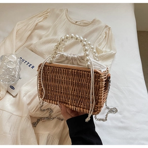 Detail of woven rattan box bag with large pearl handle and silver chain strap
