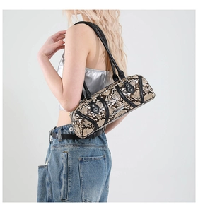 Detailed view of snake-embossed cylinder shoulder bag with silver studs and black leather straps