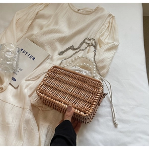 Detail of woven straw basket bag featuring pearl handle and white drawstring inner pouch