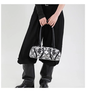 Detail of snake skin pattern cylinder handbag with rivets and metallic logo plate