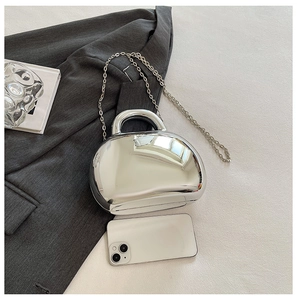Detail view of a silver metallic shell bag with a chunky handle and a chain strap