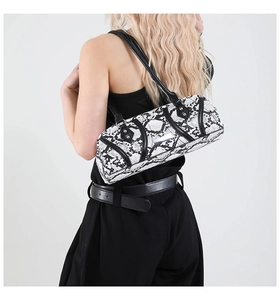Detail of snake print cylindrical shoulder bag featuring silver metal nameplate and leather strap