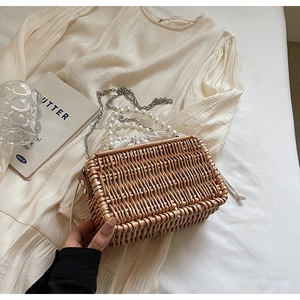 Detail of woven straw handbag featuring pearl handle and drawstring lining on soft fabric