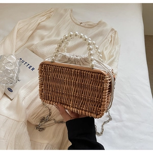 Detail of hand-woven straw beach bag with pearl beaded handle and white drawstring liner