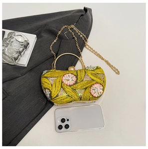 Macro detail of yellow evening bag with pink floral sequins and gold ring handle