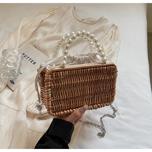 Detail of woven straw bag featuring pearl handle and white drawstring liner for summer