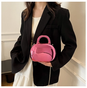 Detail of a bright pink metallic shell bag featuring a mini handle and golden chain strap