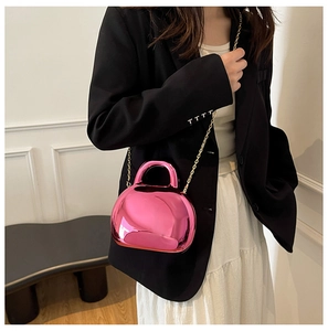 Close-up of shiny pink acrylic shell bag with metallic finish and gold chain strap