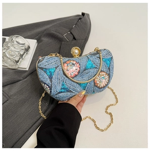 Detail of blue sequined evening clutch with floral embroidery and large pearl clasp