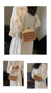 Detail of woven straw bag featuring elegant pearl handle and metal chain strap