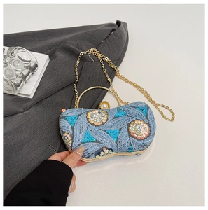 Detail of luxury sequined evening bag with blue feather patterns and pearl clasp closure