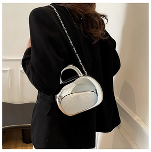 Mirror silver acrylic shell bag with metallic chain strap worn with a black blazer