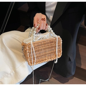 Detail of woven straw basket bag with large pearl handle and metal chain strap