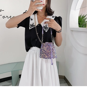 Detail of purple sequin bucket bag featuring a drawstring closure and elegant chain strap