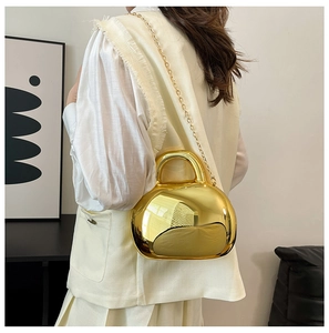 Close-up of golden mirrored acrylic shell bag showing glossy metallic texture and chain