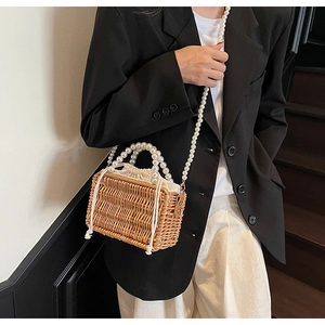 Detail of woven straw bag with cream drawstring liner and elegant pearl shoulder strap