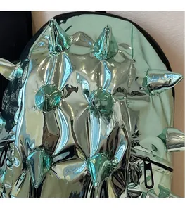 Detail shot of the glossy green metallic surface with sharp spiked stud decorations