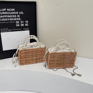 Retro woven straw tote bag with pearl handle and drawstring lining on a white stand