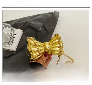 Detailed close-up of metallic gold bow-shaped mini bag with pearl bead chain strap