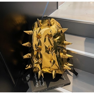 Close-up of golden shiny hedgehog backpack with punk studs on stairs with a book