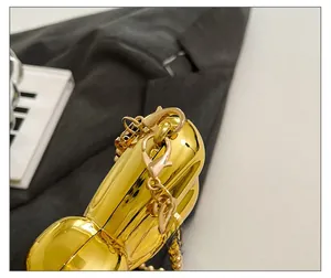Detail of golden balloon dog bag showing polished metal surface and pearl chain links
