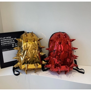 Detailed view of dual-color spiked durian backpacks in metallic gold and red finishes