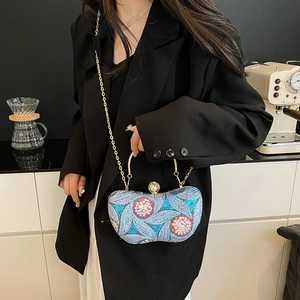 Blue sequin evening clutch bag with floral embroidery and gold metal handle shown on a model