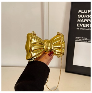 Detailed view of a metallic bow-shaped evening bag with a shiny gold mirror finish