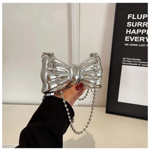 Detail of silver metal bow-shaped mini bag with glossy mirror finish and pearl chain