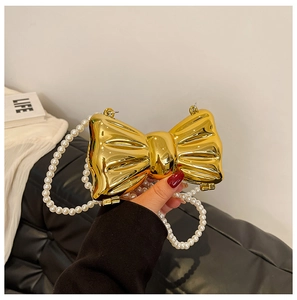Detail of metallic gold bow-shaped clutch with faux crinkle texture and pearl chain