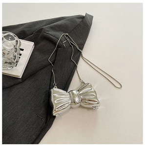 Detail of silver metallic bow bag with reflective mirror finish and pearl chain strap