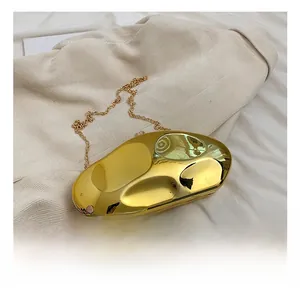 Detailed view of pebble-shaped gold acrylic clutch with polished mirror finish and chain