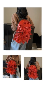 Detail of red metallic spiked backpack with large conical studs and front zipper pocket