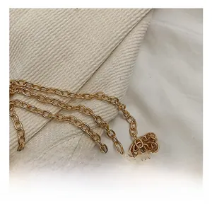 Close-up of a polished gold metal chain strap on textured beige corduroy fabric