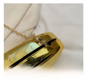 Detail of high-gloss gold acrylic evening bag featuring premium metal chain and lobster clasp