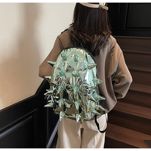 Close-up of metallic mint green backpack with spikes on wooden stairs background