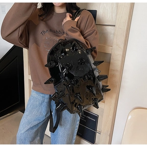 Close-up of black glossy patent leather backpack with gothic metallic cone spikes