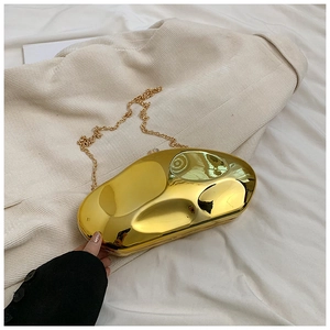 Detail of a bright gold acrylic evening bag with irregular geometric mirror finish and chain
