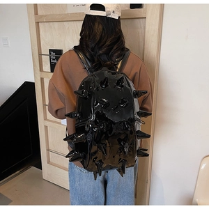 Detail showing high-gloss black punk backpack with 3D conical spikes on model back