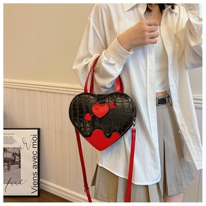 Macro detail of heart-shaped crossbody bag featuring red and black crocodile embossed leather