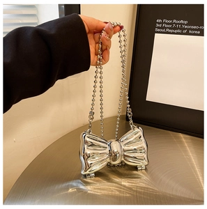 Close-up of metallic silver bow-shaped bag with spherical chain handle and mirror finish