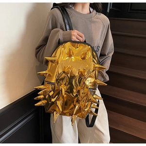 Detail of gold metallic backpack with sharp punk rivets and black zipper texture