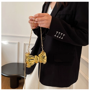Detailed macro view of the gold metallic bow mini bag with delicate pleated texture