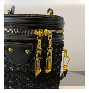 Close-up of the smooth golden double metal zippers on the black rhinestone cylinder bag