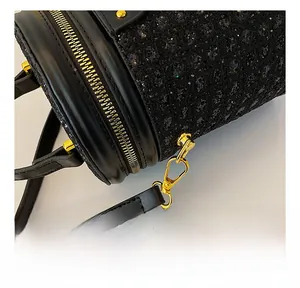 Close-up of golden metal hooks and shimmering black sequin texture on cylinder bag